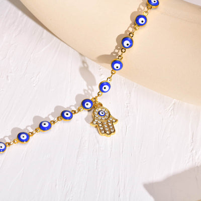Bracelet de cheville en perles de nazar boncuk bleu avec amulette khamsa posé sur une assiette beige Kaosix