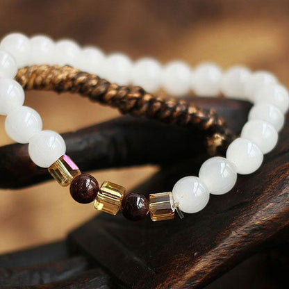 Bracelet en Calcédoine Blanche Grenat Rouge et Citrine posé sur une sculpture en bois Kaosix