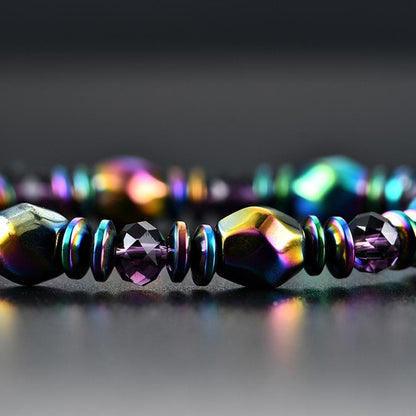 Bracelet en Hématite Arc-en-ciel posé sur un sol gris fonçé brillant et vue en gros plan sur les perles Kaosix