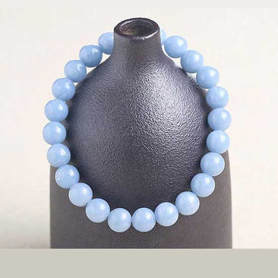 Bracelet en angélite apaisement boule 8 mm posé sur un vase gris foncé Kaosix