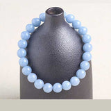 Bracelet en angélite apaisement boule 8 mm posé sur un vase gris foncé Kaosix