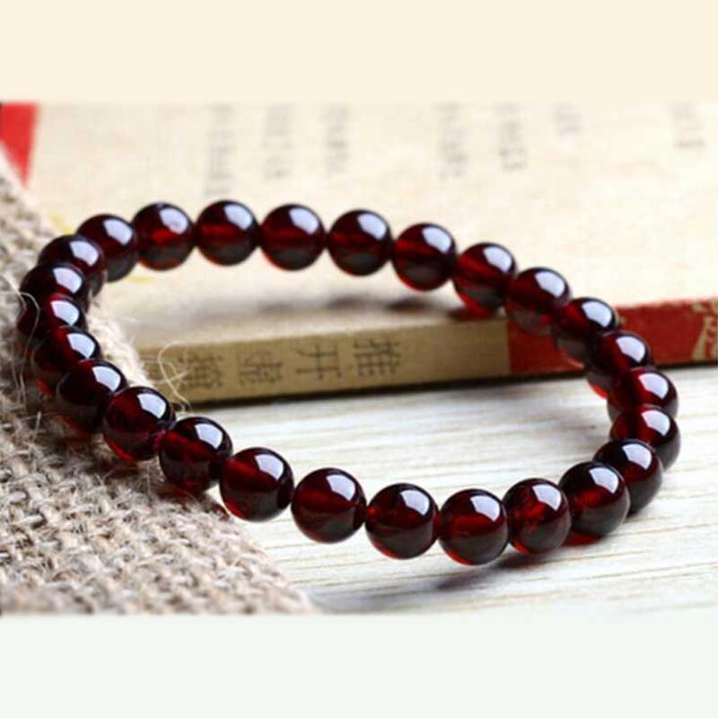 Bracelet en grenat amour posé sur un livre et sur une table Kaosix