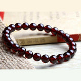 Bracelet en grenat amour posé sur un livre et sur une table Kaosix