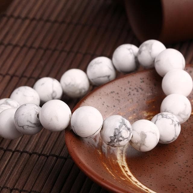 Bracelet en howlite calme boule 8 mm posé sur une assiette marron Kaosix