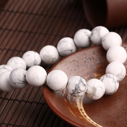 Bracelet en howlite calme boule 8 mm posé sur une assiette marron Kaosix