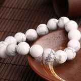 Bracelet en howlite calme boule 8 mm posé sur une assiette marron Kaosix