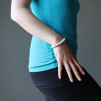 Bracelet en howlite calme boule 8 mm sur un poignet de femme avec le bras le long de son corps Kaosix