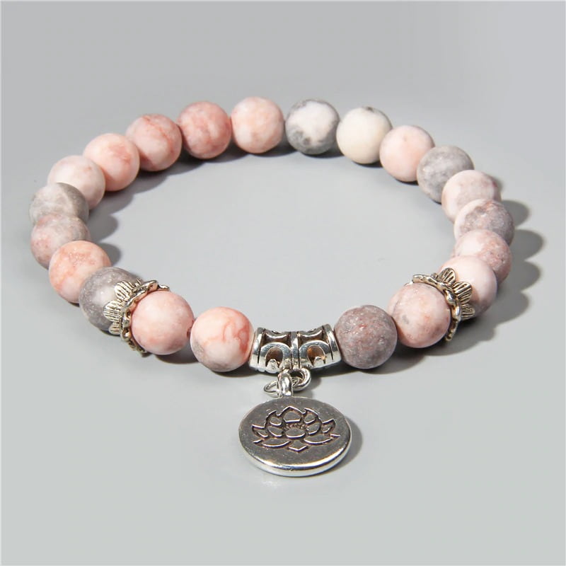 Bracelet en jaspe rose et sa breloque fleur de lotus sur fond gris Kaosix