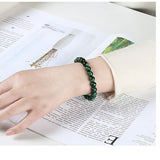 Bracelet en œil de tigre vert énergisant au poignet d'une jeune fille en train de lire un magazine Kaosix