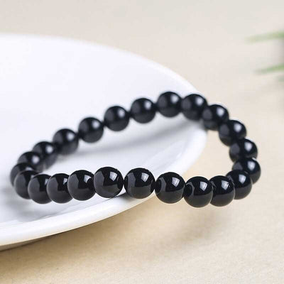 Bracelet en tourmaline noire ancrage boule 8 mm posé sur une assiette blanche sur une table Kaosix