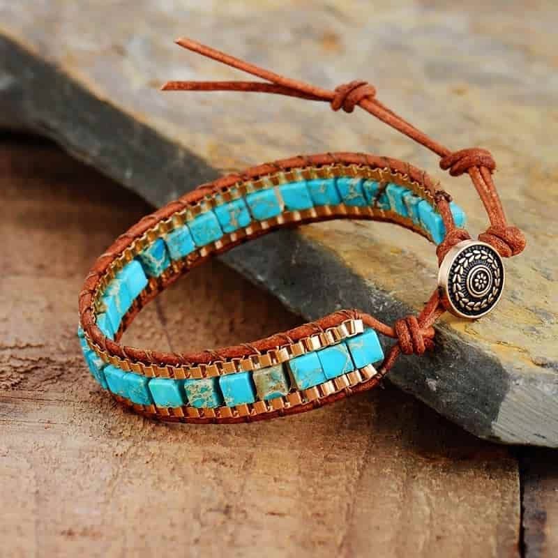 Bracelet femme turquoise perle cubique et cuir posé à moitié sur une pierre et à moitié sur une planche en bois Kaosix