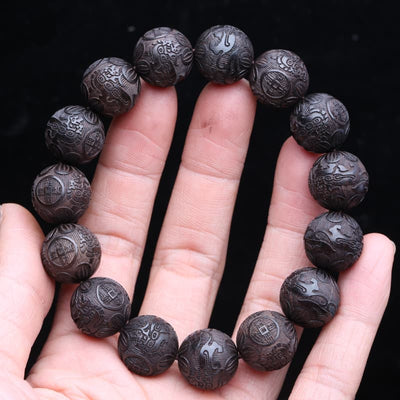 Bracelet feng shui Pi Xiu en perles de bois noir sur les doigts d'une main Kaosix