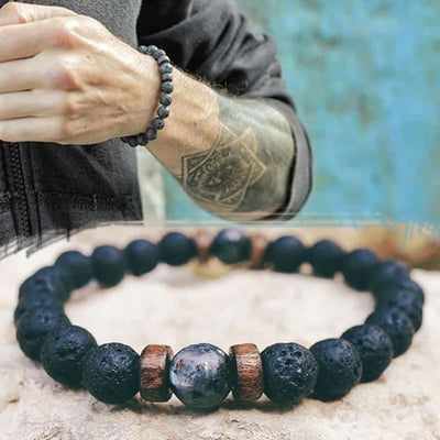 Bracelet homme en pierre de lave et en pierre de lune noire en gros plan avec un bracelet au poignet d'un homme en arrière plan Kaosix