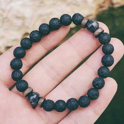 Bracelet homme en pierre de lave et en pierre de lune noire posé sur une main d'homme en gros plan Kaosix
