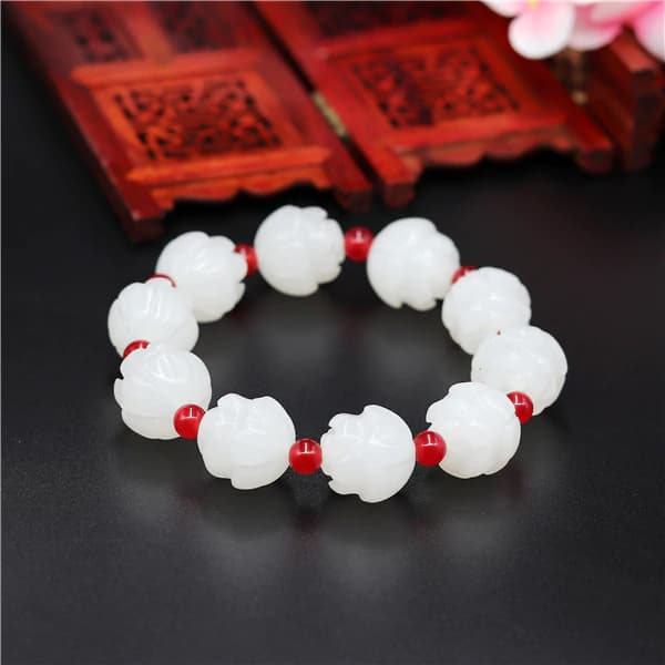 Bracelet jade blanc lotus pose sur une table noire Kaosix