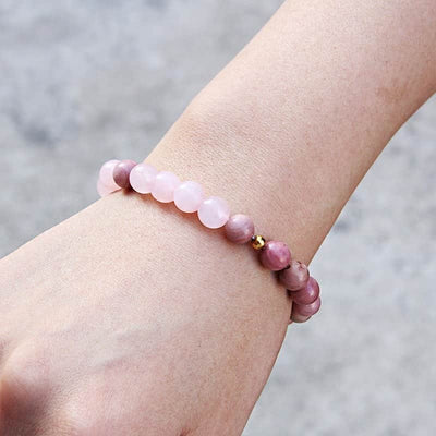 Bracelet joie et amour en quartz rose et rhodonite en gros plan sur le poignet d'une jeune fille Kaosix