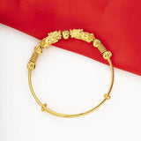 Bracelet jonc doré double Pi Xiu posé sur un sol blanc et une nappe rouge vue de dessus Kaosix