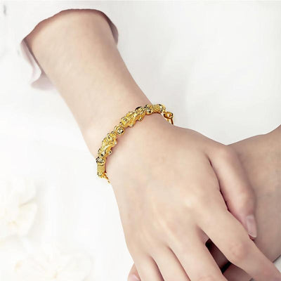 Bracelet jonc doré double Pi Xiu sur un poignet de jeune fille vue de loin Kaosix