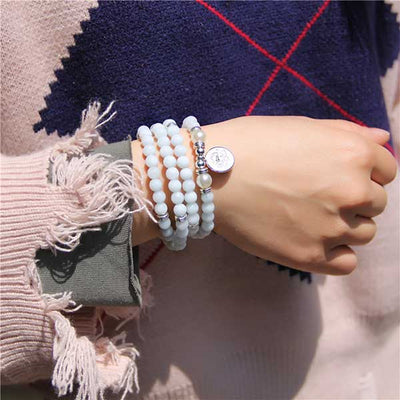 Bracelet mala 108 perles en aigue-marine avec symbole du lotus enroulé autour du poignet d'une dame Kaosix
