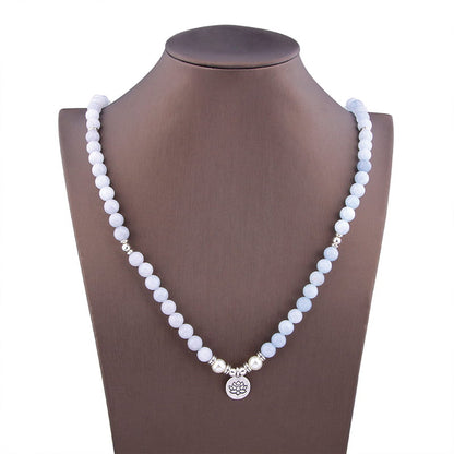 Bracelet mala 108 perles en aigue-marine avec symbole du lotus posé autour du coup et des épaules d'un buste mannequin Kaosix