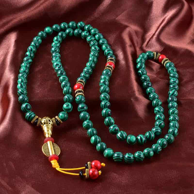 Bracelet mala 108 perles en malachite à plat sur une nape soyeuse Kaosix