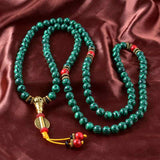 Bracelet mala 108 perles en malachite à plat sur une nape soyeuse Kaosix
