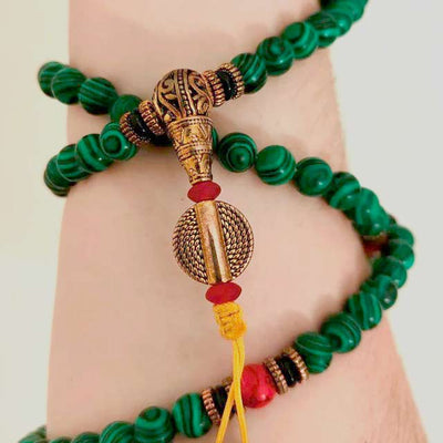 Bracelet mala 108 perles en malachite sur poignet de femme Kaosix