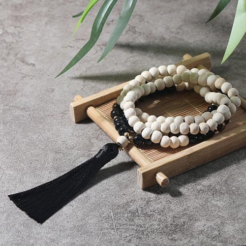 Bracelet mala 108 perles en œil de tigre et en bois posé à plat sur une petite planche en bois Kaosix