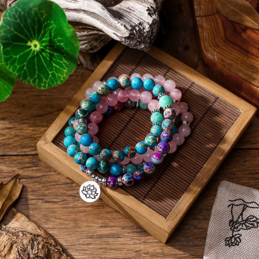 Bracelet mala 108 perles quartz rose amazonite jaspe turquoise posé sur une boite en bois et sur un plancher en bois Kaosix