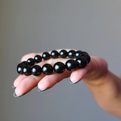 Bracelet obsidienne noire “stabilité” posé sur la peaume d'une main de femme Kaosix