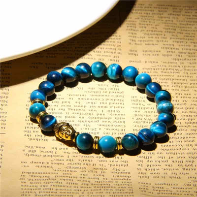Bracelet œil de tigre bleu tête de Bouddha sur papier journal Kaosix