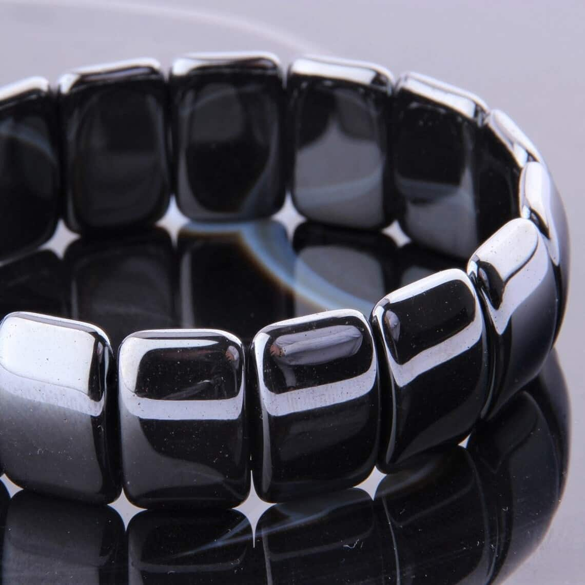 Bracelet pierres plates (plaquettes) obsidienne noire en gros plan posé sur une surface grise brillante Kaosix