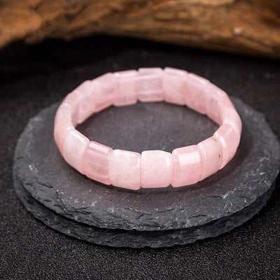 Bracelet pierres plates (plaquettes) quartz rose posé sur une pierre plate de couleur grise Kaosix