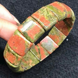 Bracelet pierres plates (plaquettes) unakite sur la tranche tenue par des doigts de femme Kaosix