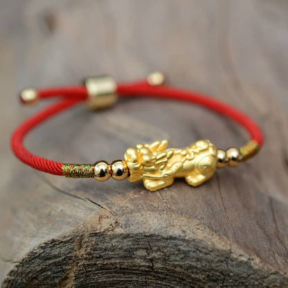 Bracelet rouge Pixiu Feng Shui sur un tronc d'arbre Kaosix