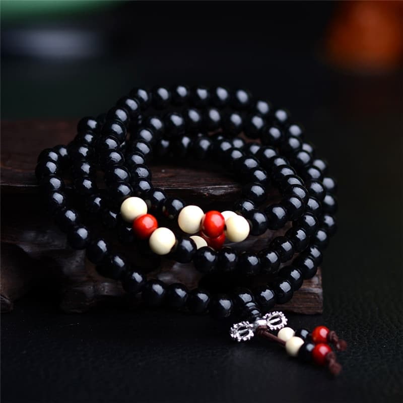 Bracelets mala de prière en bois de santal colour noir 108 perles posé sur un socle en bois Kaosix.