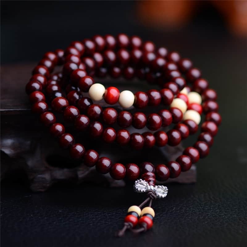 Bracelets mala de prière en bois de santal colour rouge 108 perles posé sur un socle en bois Kaosix.