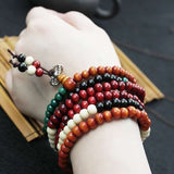 Bracelets mala de prière en bois de santal multi-couleur 108 perles sur le poignet d'une jeune fille Kaosix.