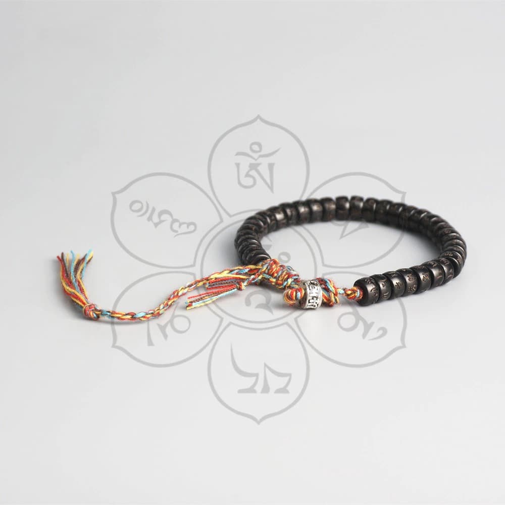 Bracelet tibétain coquille de coco sur fond gris avec caractères du mantra Om Kaosix