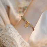 Bracelet tressé perles vertes en jade de Hetian et amulette dorée au bras d'une jeune fille Kaosix