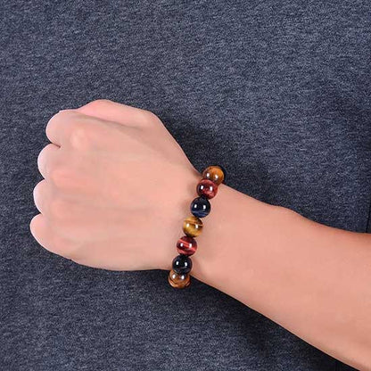 Bracelet triple protection œil de tigre œil de faucon et œil de taureau au poignet d'un homme contre un tshirt gris Kaosix