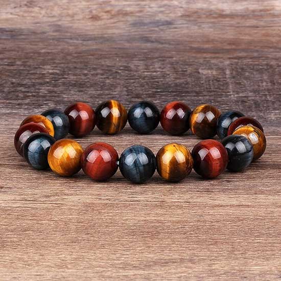 Bracelet triple protection œil de tigre œil de faucon et œil de taureau posé sur un sol en bois Kaosix