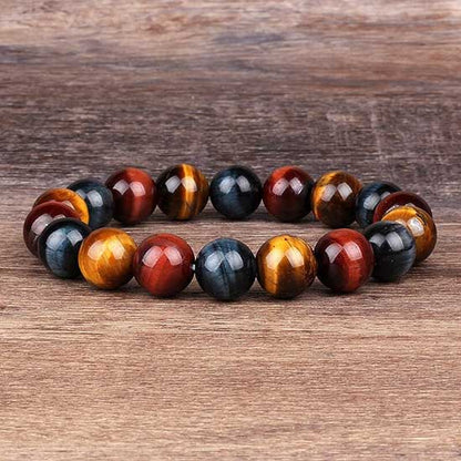 Bracelet triple protection œil de tigre œil de faucon et œil de taureau posé sur un sol en bois Kaosix
