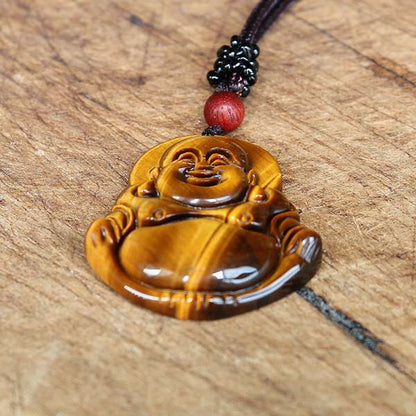 Collier pendentif Bouddha Rieur en Œil de Tigre posé à plat sur une table en bois Kaosix