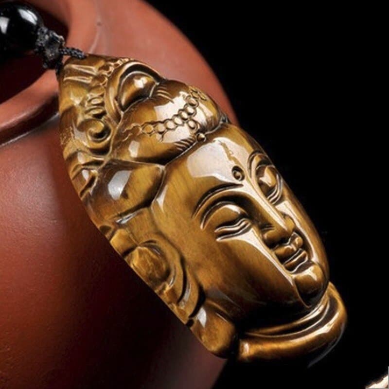 Collier pendentif Guanyin (Bouddha) en Œil de Tigre posé contre une théière rouge Kaosix