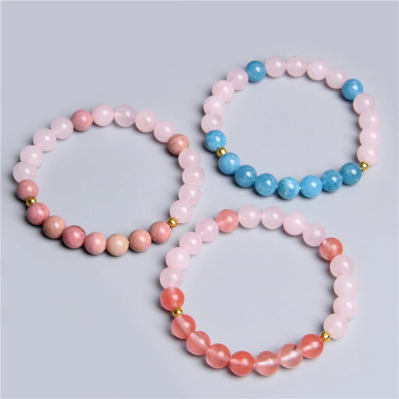 Deux bracelets joie et amour en quartz rose et rhodonite posé à plat sur une surface grise Kaosix