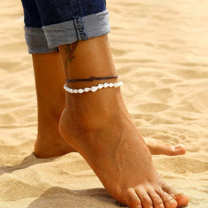 Double bracelet de cheville en coquillages buccin et cordon de cuir autour de la cheville d'une femme ouvert Kaosix