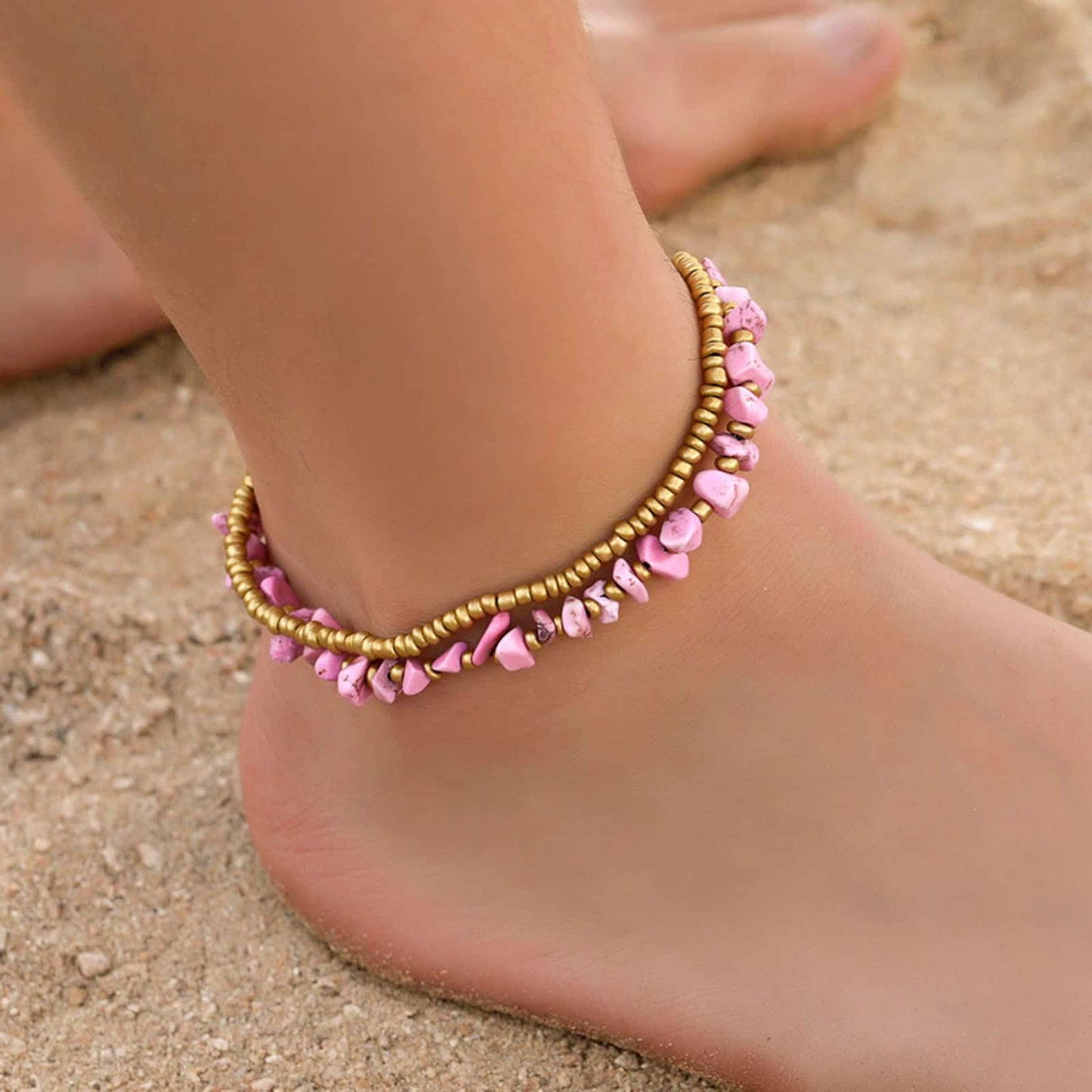 Double bracelet de cheville en éclats de tourmaline rose et perles de cuivre autour d'une cheville de femme pieds nus Kaosix