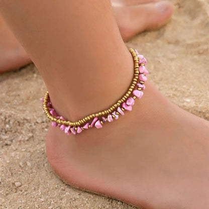 Double bracelet de cheville en éclats de tourmaline rose et perles de cuivre autour d'une cheville de femme pieds nus Kaosix