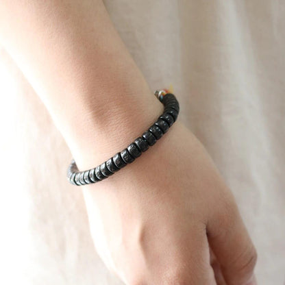Gros plan du bracelet tibétain coquille de coco mantra sur le poignet d'une femme Kaosix